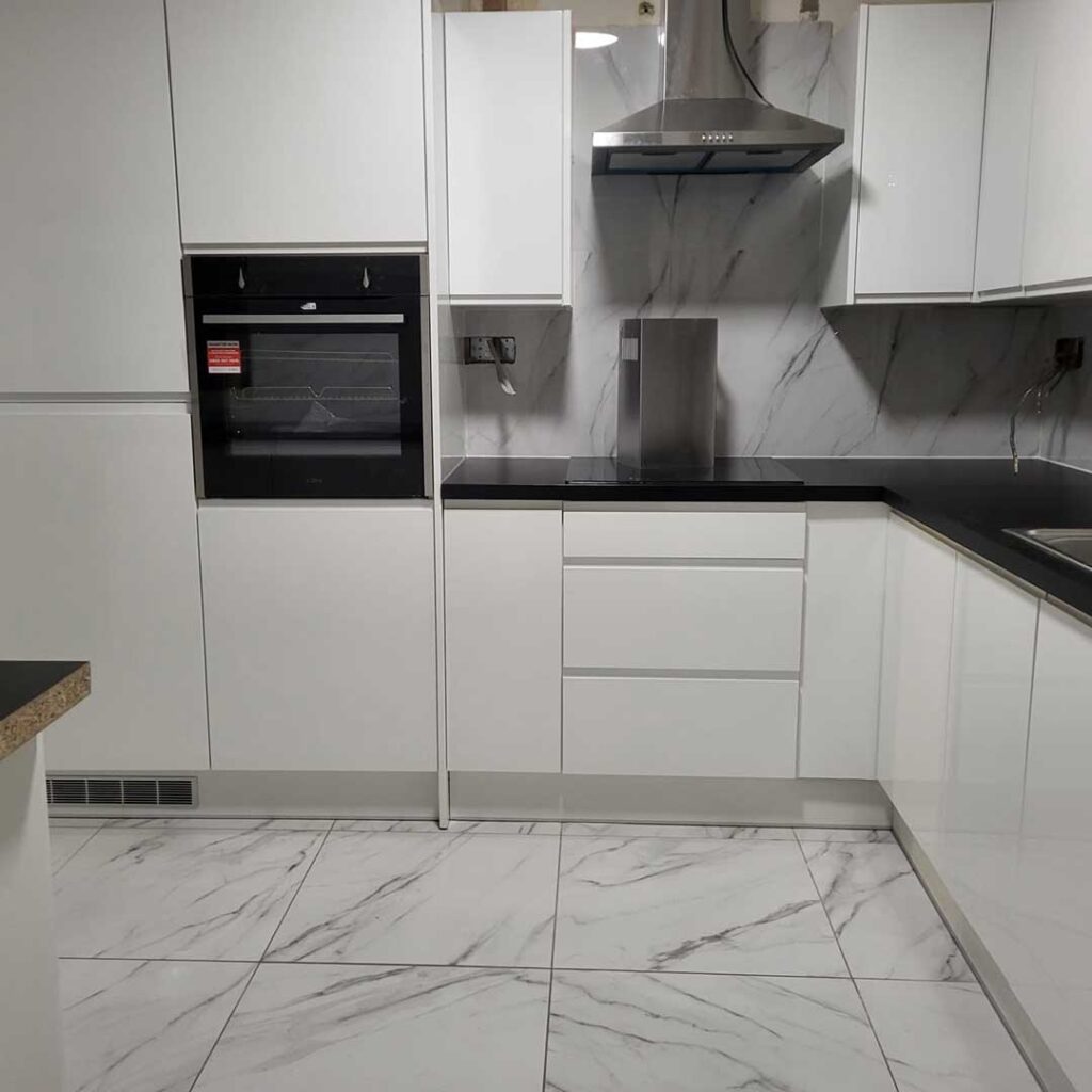kitchen fitted in Lewisham home, white cabinets with black tops.